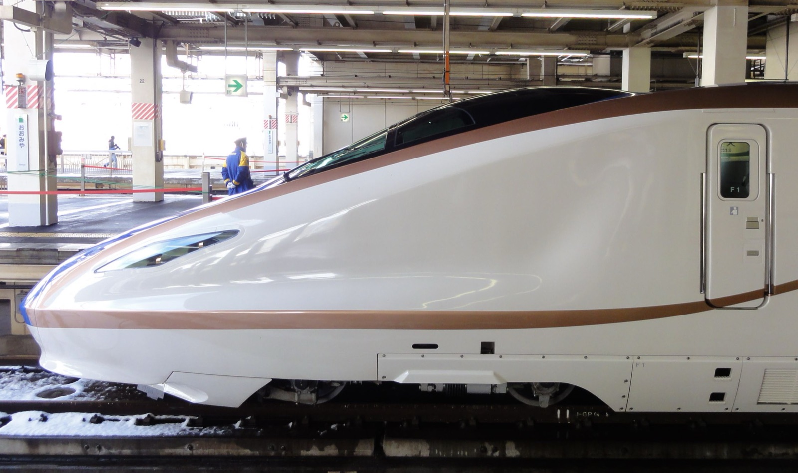 Long white-and-blue nose of a Shinkansen E7 series bullet train at the platform at Ōmiya Station